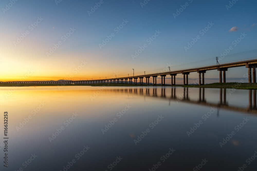Beautiful sunset scene of railway bridge in lake of pasak Dam ,