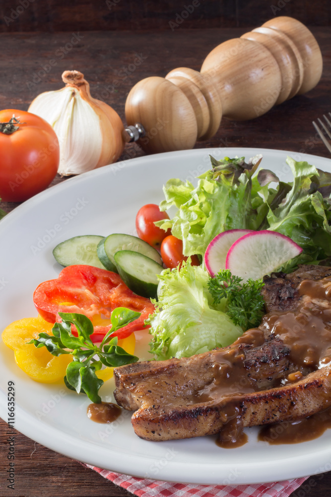 close up to Kurobuta pork chop steak and vegetable on wooden tab close up to Kurobuta pork chop steak and vegetable on wooden tab