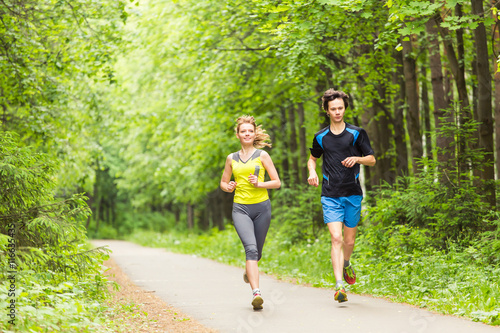 Couple running outdoors. Woman and man runners jogging together outside in full body length.