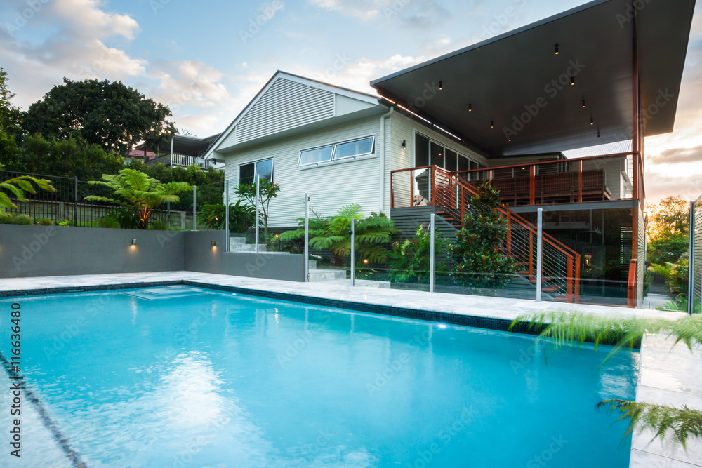 Fototapeta premium Luxury poolside closes up with modern house with green trees