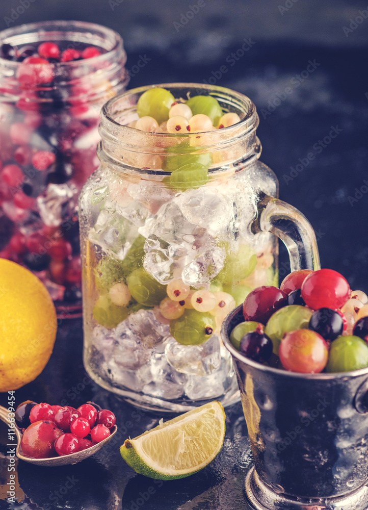 Fresh berries with ice in mason jar on dark background Fresh berries with ice in mason jar on dark background