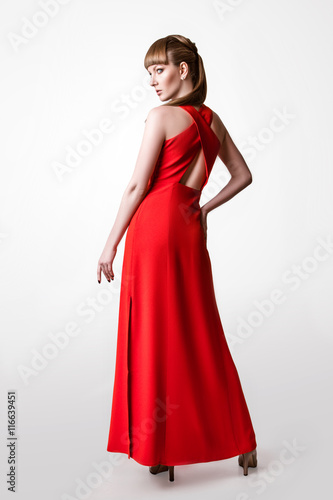 beautiful woman model posing in simple elegant red dress in the studio on white background