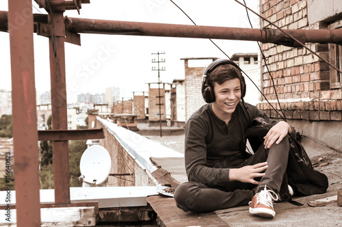 teenager on the roof of the house in the headphones