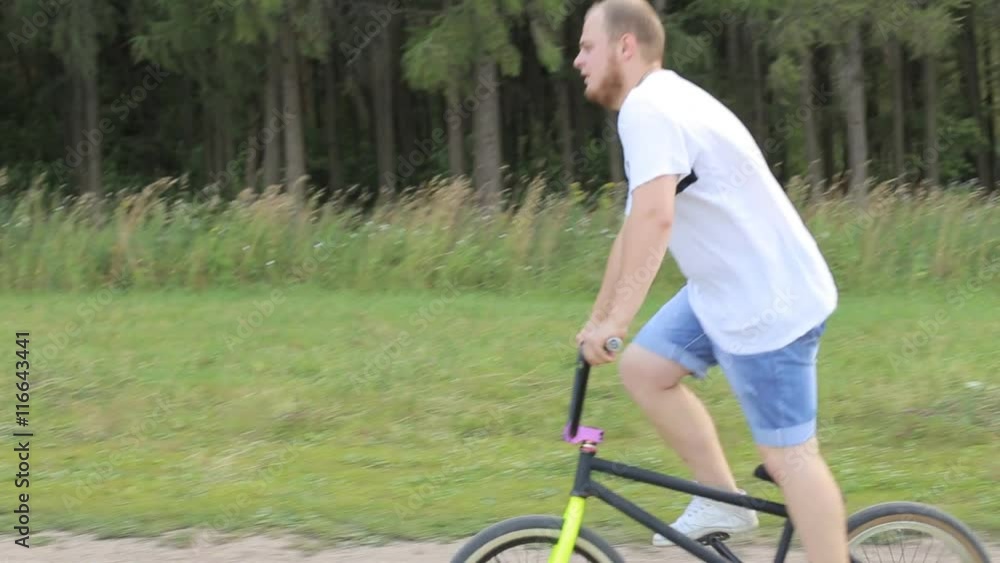 Young man cycling a sunny park on street in summertime Young man cycling a sunny park on street in summertime