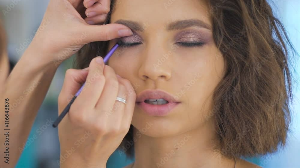 Professional makeup artist applying make up on a beautiful young face for a photoshoot Professional makeup artist applying make up on a beautiful young face for a photoshoot