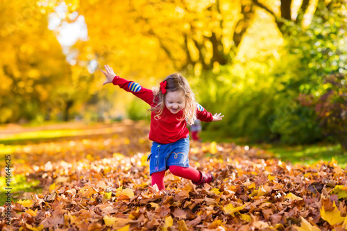 Little girl playing in autumn park