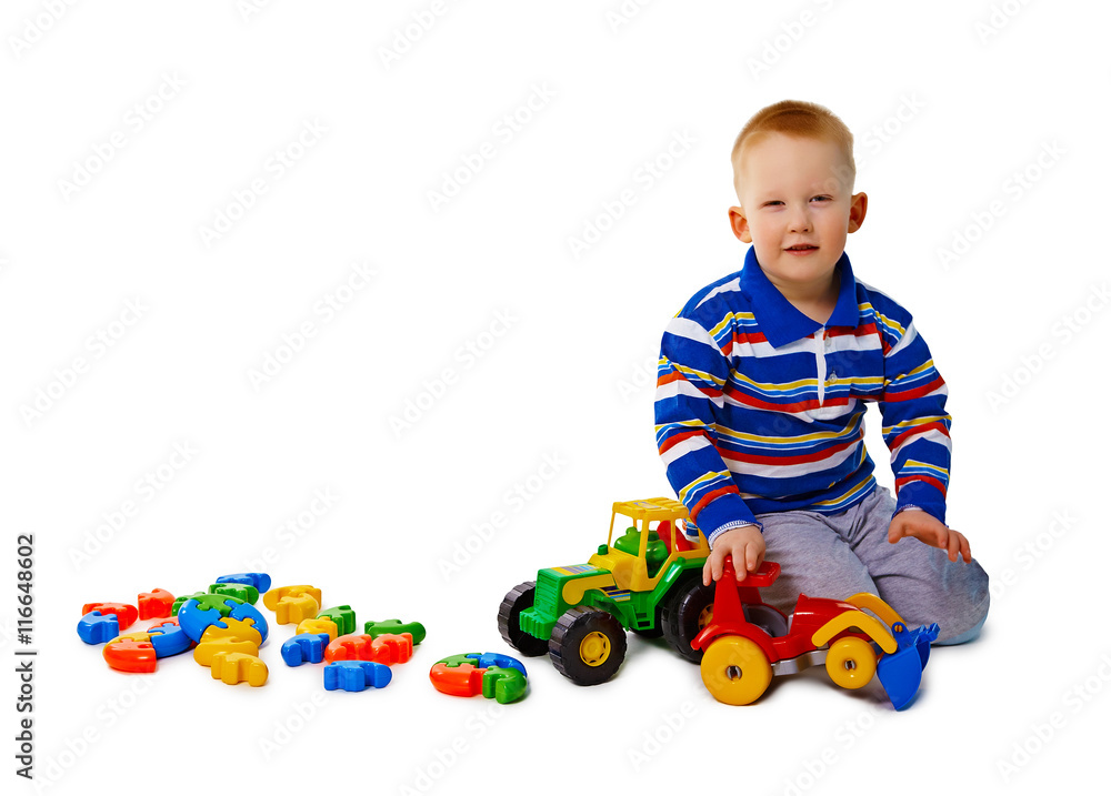 Boy sits on white background with toys Boy sits on white background with toys