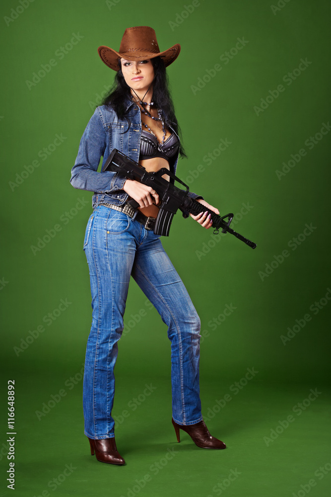 Beautiful woman in jeans with rifle on green Beautiful woman in jeans with rifle on green