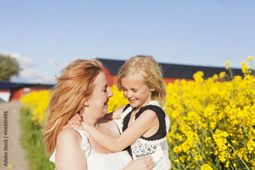 Happy woman carrying daughter at oilseed rape field Happy woman carrying daughter at oilseed rape field