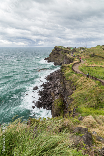 View of rugged landscape and coastal walkway next to the Songaksan Mountain on Jeju Island in South Korea.