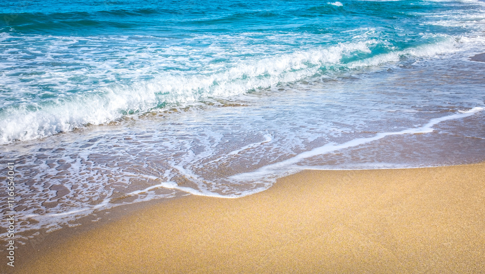Strand mit türkisblauem Wasser und goldenem Sand im Sommer