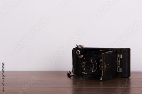 Vintage camera on wooden surface against light background