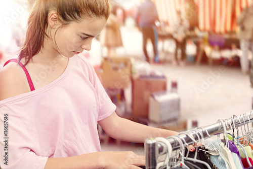teenage girl looking for clothes at a flea market