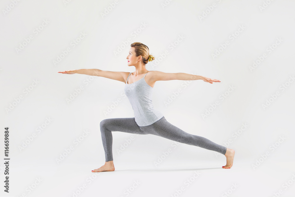 Fototapeta premium Beautiful young woman doing yoga on a gray studio background