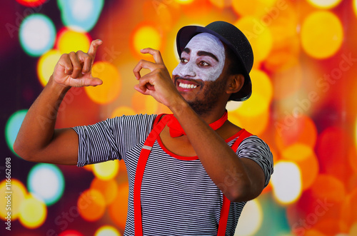 Fotografie Pantomime man wearing facial paint posing for camera, using hands interacting bo