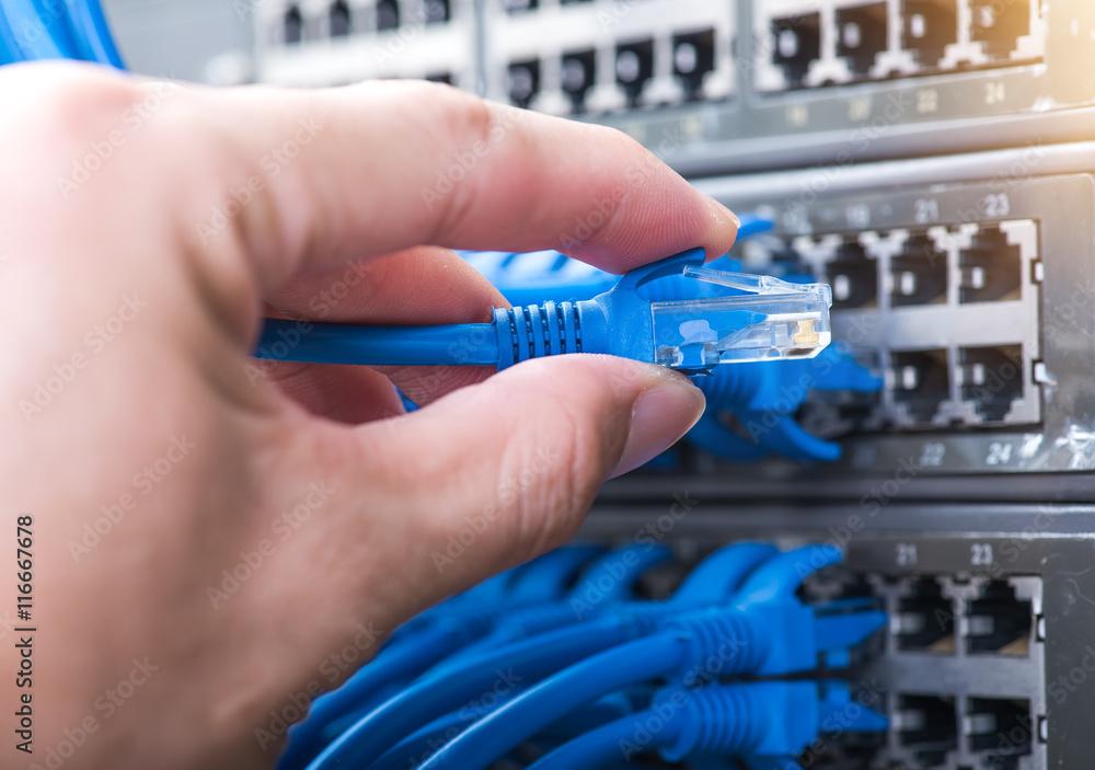man working in network server room with fiber optic hub for digi