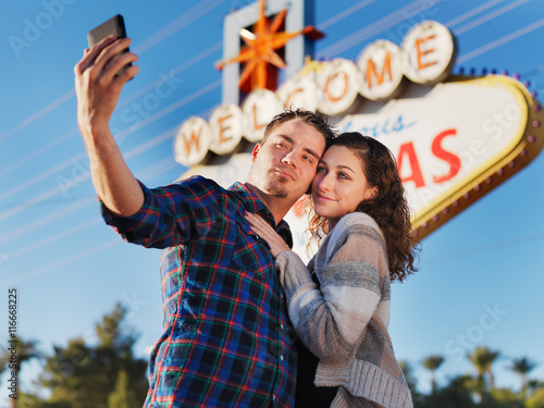 Photography couple in front of las vegas sign taking selfie with smartphone