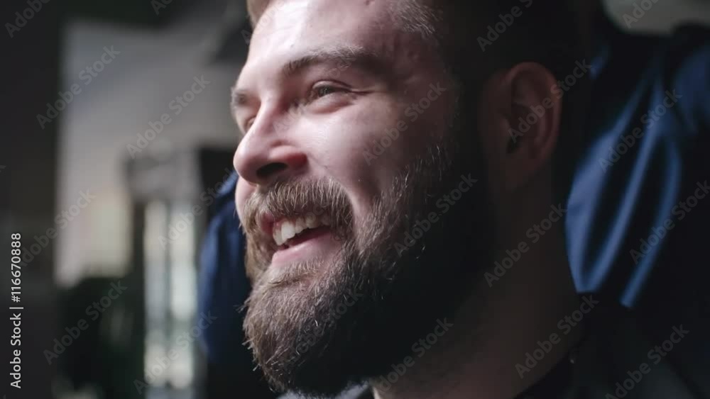 Young bearded man laughing while barber making his hair with gel Young bearded man laughing while barber making his hair with gel