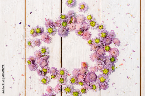 Beautiful circlet of purple aster flowers on white wooden background. Delicate floral composition with free space in center of wreath