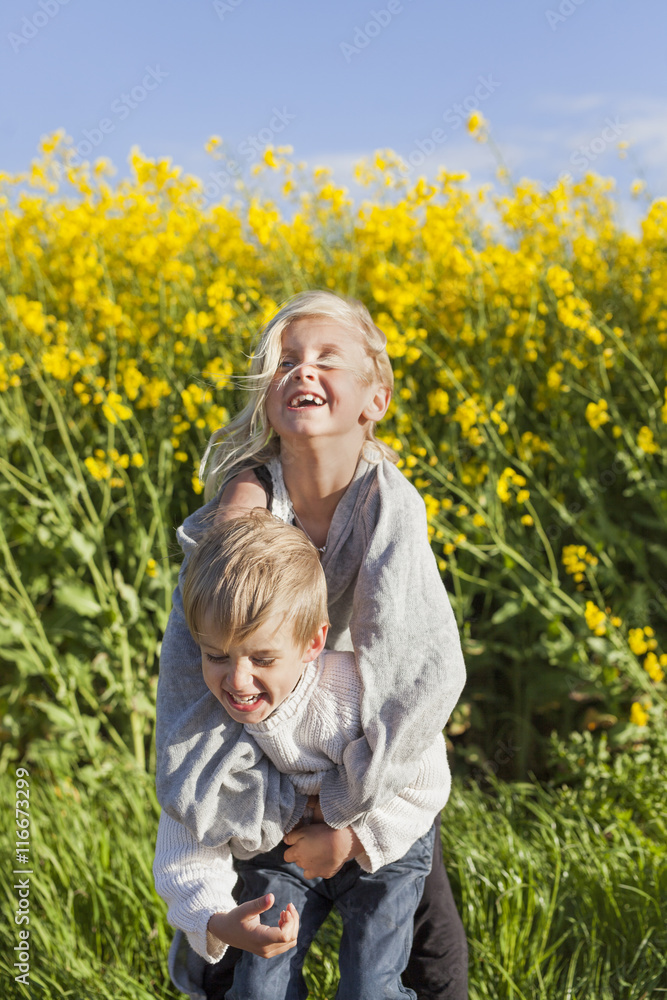 Brother and sister hugging in canola field Brother and sister hugging in canola field