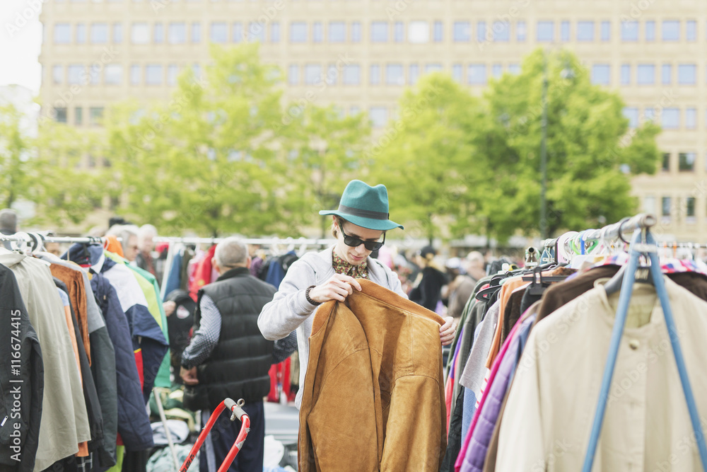 Young man holding jacket while shopping at flea market Young man holding jacket while shopping at flea market