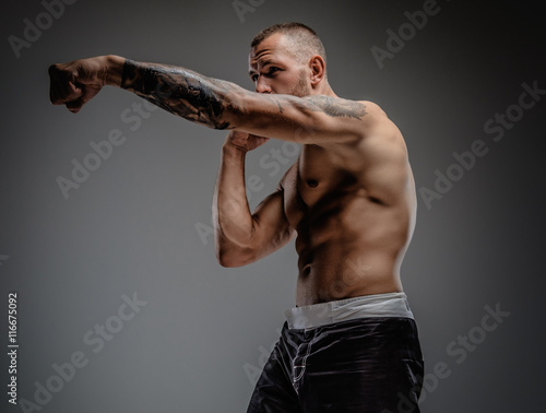 Tattooed fighter isolated on a grey background. photo