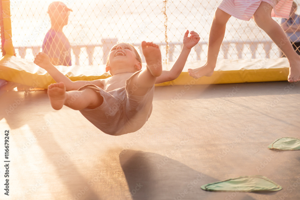 children jumping on trampoline on coast - obrazy, fototapety, plakaty 