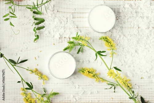 Body care cream in sample jars, sea salt, green herb. Top view, white spa set background. 