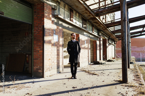 Lonely businessman in front of abandoned industrial building