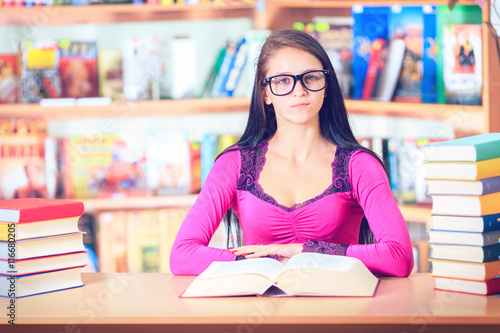 girl student with glasses reading books in the library
