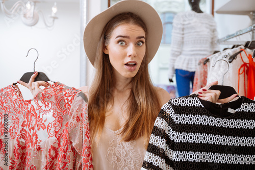 Valokuva Confused woman doing shopping and choosing dress in clothing store