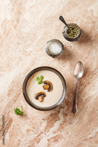 Cream homemade mushroom soup in a black plate with parsley. Marb
