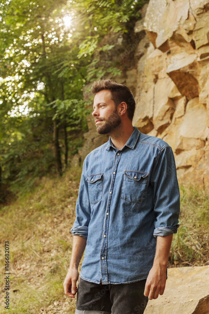 Man wearing denim shit standing near rock Man wearing denim shit standing near rock