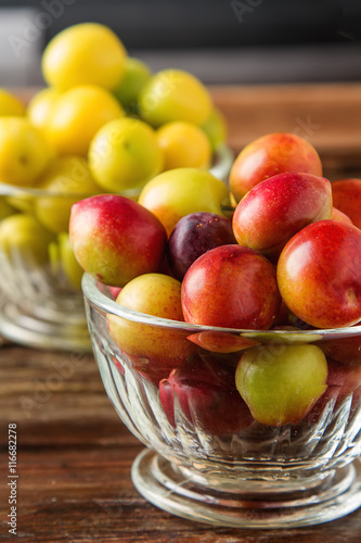 Ripe plums in a glass. Dark wood background