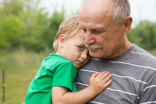 Sad little child, boy, hugging his grandfather at outdoors. Family concept     © ulza