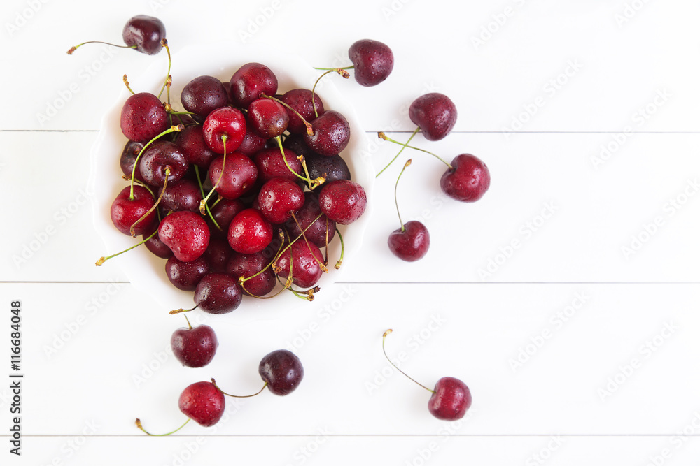 Ripe red cherries with water drops in bowl on a white background. Top view with copyspace Ripe red cherries with water drops in bowl on a white background. Top view with copyspace