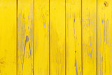 Vertical background of the wooden planks with cracked yellow paint