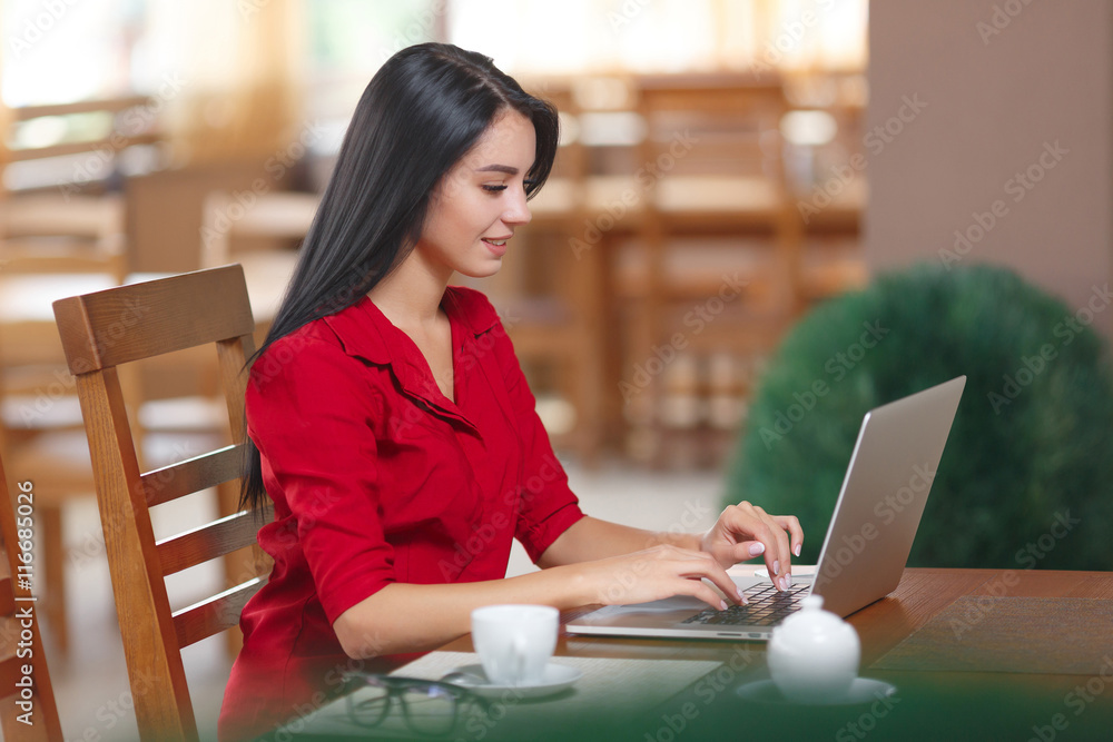 Young business woman uses laptop in cafe