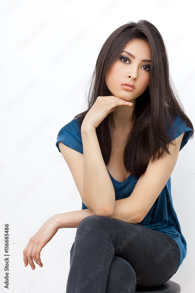 Annoyed asian woman sitting and lookin at camera on white background Annoyed asian woman sitting and lookin at camera on white background