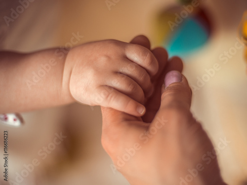 A new mother is holding his newborn infant baby's hand