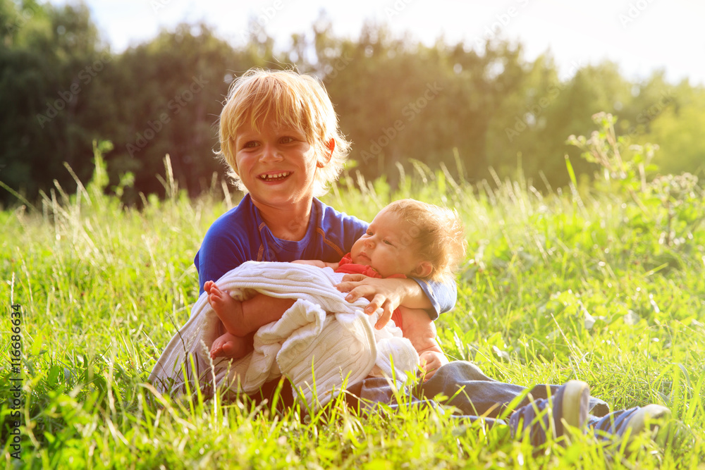 Fototapeta premium little boy holding newborn sister in summer nature