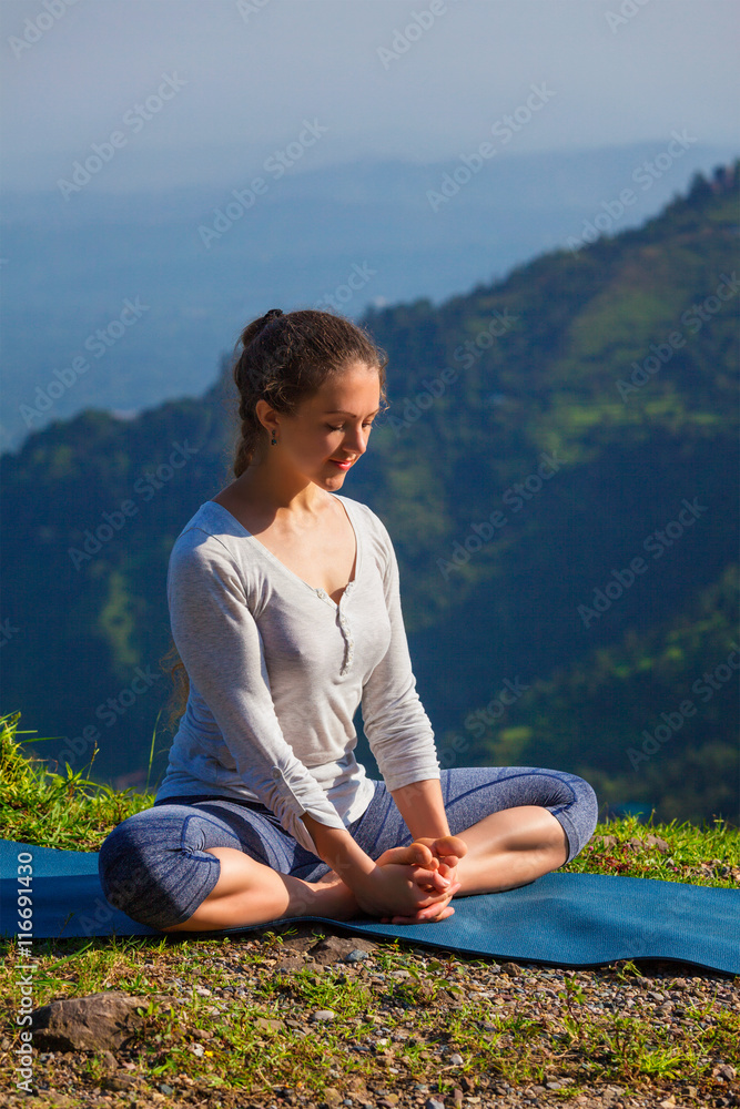 Sporty fit woman practices yoga asana Baddha Konasana outdoors