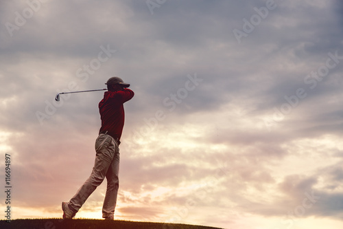 silhouette of man golfer with golf club at sunset © alexsokolov