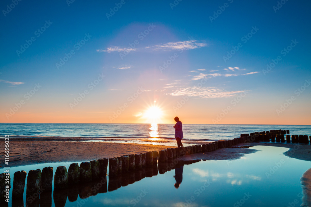 Obraz premium Sunset at Baltic sea, view on old breakwater piles.