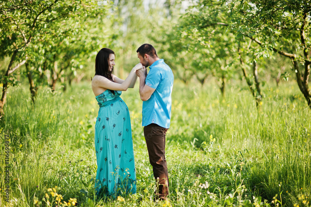 Fototapeta premium Happy pregnant couple at turquoise dress on the garden