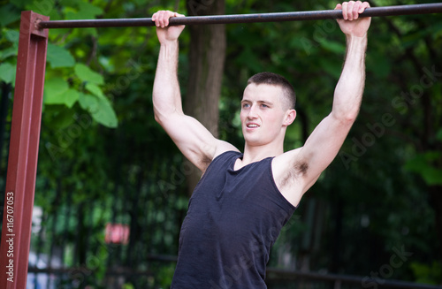 strong man doing pull-ups on a bar outdoor