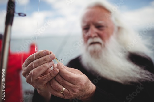 Close up of fisherman adjusting fishing hook photo