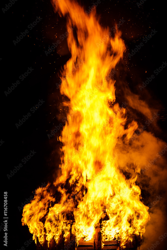Obraz premium Wooden house roof in fire on black background