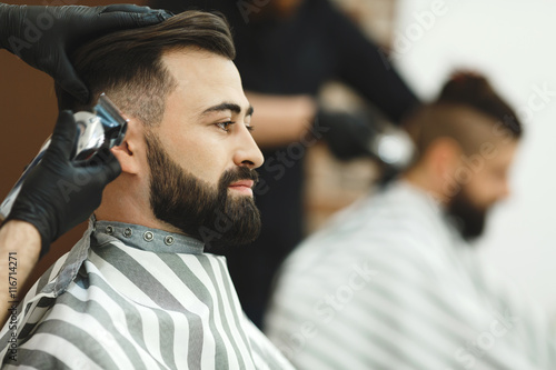 Man with dark hair doing a haircut © veles_studio