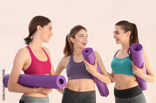 Young women with mats in gym
